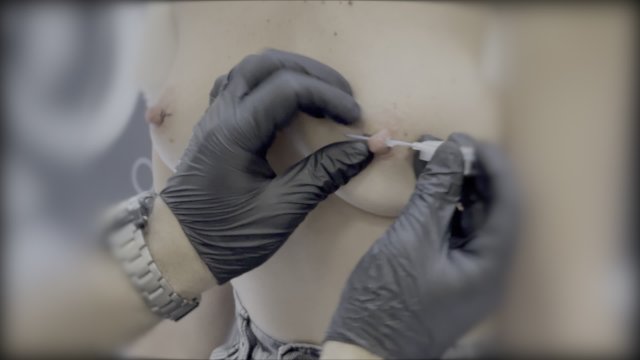 Sexy wife piercing her nipples in a piercing studio. Close up.