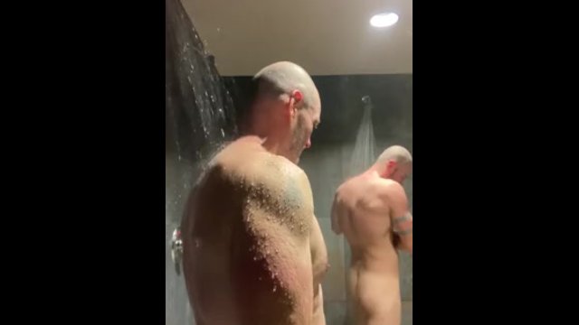 Beefy men shower together in gym locker room
